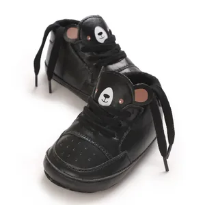 Vue détaillée de baskets noires pour bébés avec un design de visage d'ours de dessin animé