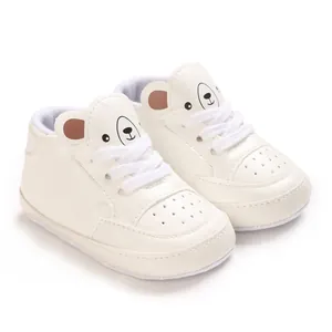 Vue détaillée de baskets blanches pour bébé avec un motif d'ours mignon sur la languette.