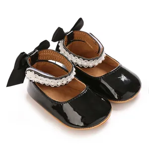 Close-up of black patent leather baby Mary Jane shoes with bow and pearl detail