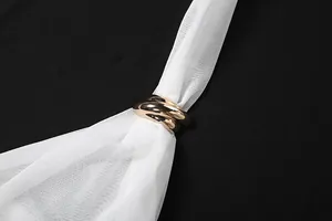 Detailed view of the elegant rose gold intertwined ring buckle on white mesh halter top.