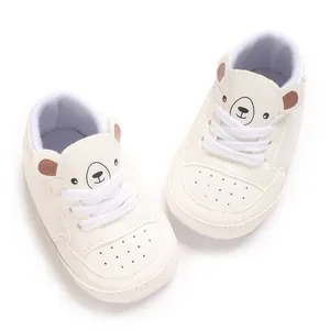 Vue détaillée de chaussures blanches pour bébé avec un joli motif de tête d'ours de dessin animé.