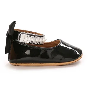 Side view of black patent leather baby girl princess shoe with lace and pearl strap