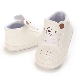 Gros plan de baskets blanches pour bébé avec un joli visage d'ours sur la languette.