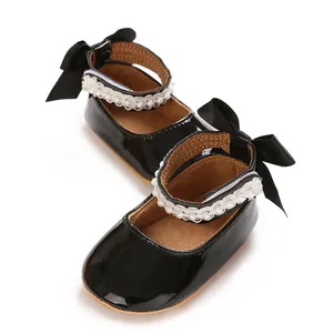 Detail showing black patent leather baby princess shoes with pearl trim and bows