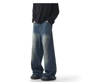 Detail of men's loose wide-leg washed blue jeans with a vintage yellow-mud dyed finish