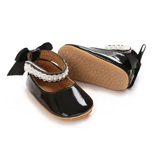 Black patent leather baby princess shoes with pearl straps and bow details.