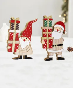 Detailed macro view of wooden Santa and gnome figurines with glitter gift boxes.