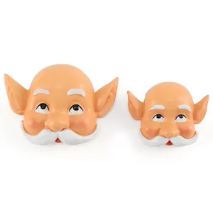 Close-up detail of two resin Santa and elf face ornaments with white mustaches and eyebrows