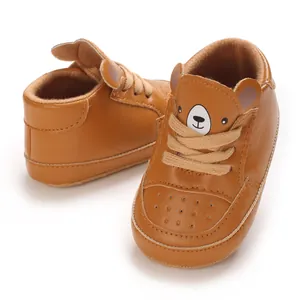 Gros plan de baskets marron pour bébé avec un motif d'ours mignon sur la languette.