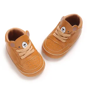 Vue détaillée des chaussures de sport marron pour bébé avec un joli motif d'ours en peluche.