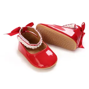 Detailed close-up view of red shiny PU baby princess shoes with pearls and silk bows