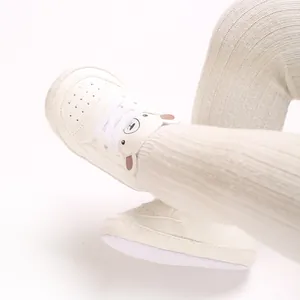 Détail rapproché de baskets blanc cassé pour bébé avec un joli motif d'ours