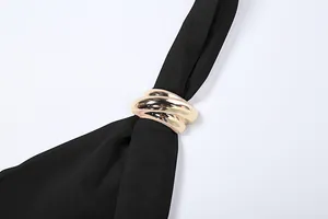 Detail view of the golden metallic triple ring accessory on a black mesh halter top fabric