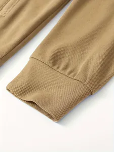 Nahaufnahme der Waffelstrickstruktur und des Rippbündchens einer khakifarbenen Herrenjacke