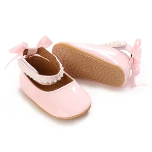 Close-up of pink PU baby girl princess shoes with pearl straps and decorative bows