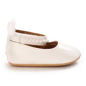Close-up detail of white baby girl princess shoe featuring elegant pearl strap and bow.