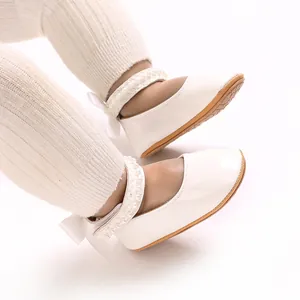 Detail view of white PU leather baby girl princess shoes with pearl straps and bow