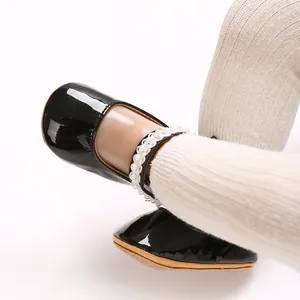 Detail shot of black PU patent leather baby girl princess shoes with pearl ankle straps.
