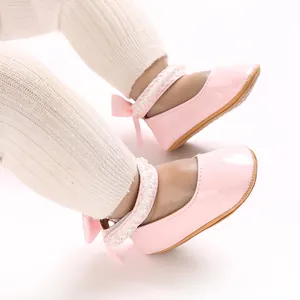 Detail of pink patent leather baby princess shoes with lace strap and bow.