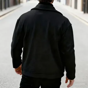 Achteraanzicht van een man die een minimalistische zwarte wollen jas met reverskraag draagt