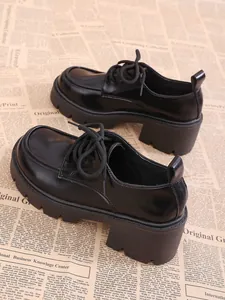 Gros plan de mocassins à plateforme noirs avec semelles épaisses sur journal vintage