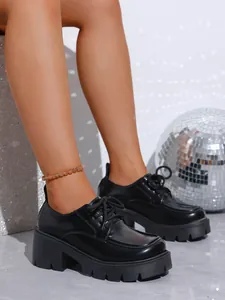 Gros plan détaillé sur des mocassins noirs à plateforme pour femmes avec design à lacets.