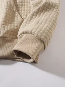 Detailaufnahme des beigen Waffelstrickstoffs und des Rippbündchens am Herren-Sweatshirt