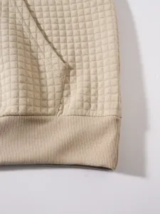 Makroansicht der Waffelstrickstruktur und des Rippsaums eines beigen Kapuzenpullovers