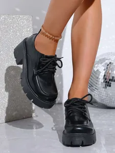 Détail de mocassins noirs à semelle plateforme épaisse et lacets stylés