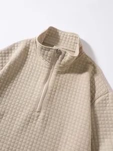 Nahaufnahme des beigen Waffelstrick-Sweatshirts mit Stehkragen und Halbreißverschluss.