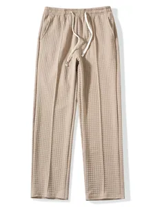 Detailed macro view of beige waffle knit texture on loose fit drawstring pants.