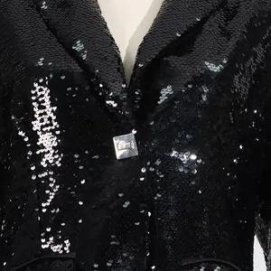 Detail shot of black sequined blazer showing fine sequin texture and metal button.