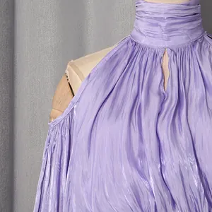 Detail eines lila schimmernden Neckholder-Oberteils mit Faltenstruktur und Cut-out-Schultern