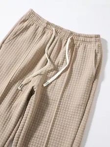 Close-up detail of waffle-knit sweatpants featuring elastic waist and white drawstring