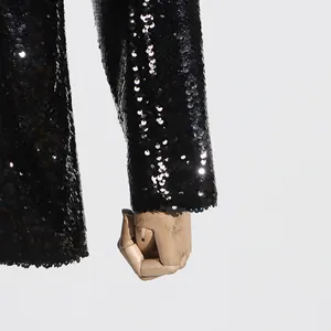 Close-up detail of a fashionable black sequined blazer sleeve with shimmering texture