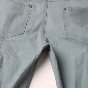 Macro view showing the back pockets and copper rivets on high-waist light grey denim jeans