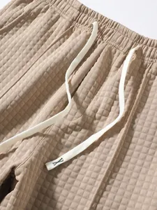 Close-up detail of waffle texture and white drawstring on khaki casual pants.