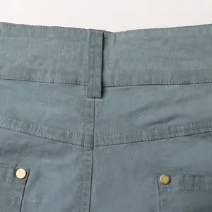 Close-up detail of high-waisted jeans showing stitching, belt loops, and metal rivets.