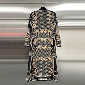 Vista dettagliata del cappotto di lusso nero con ricami dorati e perline ornate.