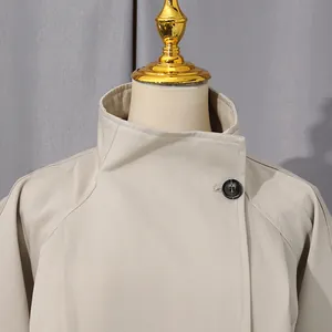 Dettaglio di un trench lungo beige con collo alto a lupetto e chiusura a bottone