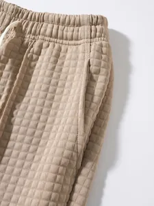 Close-up of men's khaki waffle knit jogger pants with elastic drawstring waistband.