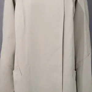 Dettaglio ravvicinato di un trench lungo beige da donna con trama del tessuto