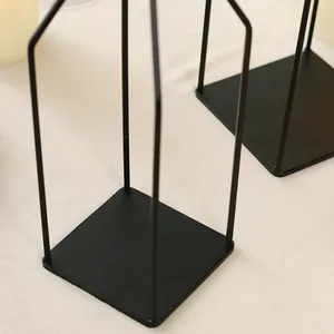 Dettaglio di un portacandele geometrico minimalista in ferro nero con base quadrata.