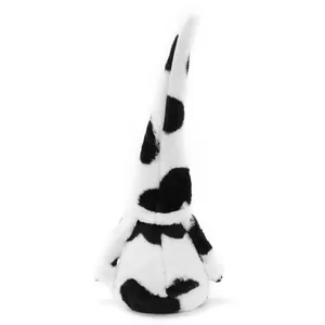 Detailed view of a plush cow-print gnome doll with a tall pointed hat and soft fabric