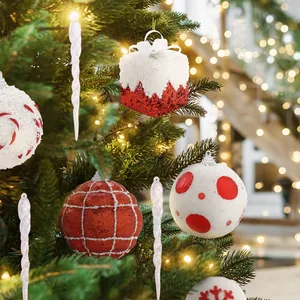 Festive red and white glitter Christmas ornament set hanging on a lush green tree