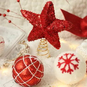 Red glittery star tree topper and snowflake ornaments in a festive snow scene setting.