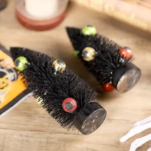 Zwei schwarze Halloween-Miniaturbäume mit gruseligen glitzernden Augen auf Holzgrund