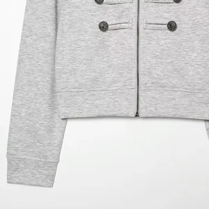 Detail of a grey casual jacket with decorative lion buttons and a sturdy metal zipper.