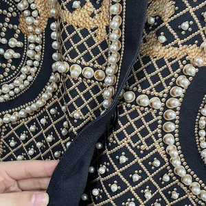 Dettaglio delle decorazioni in perla su una giacca nera con motivi dorati di lusso