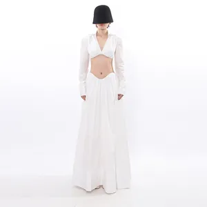 Avant-garde white two-piece set featuring a cropped long sleeve top and pleated maxi skirt.